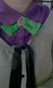 A green continental or "lady" tie, worn with a purple blouse and sage cardigan.